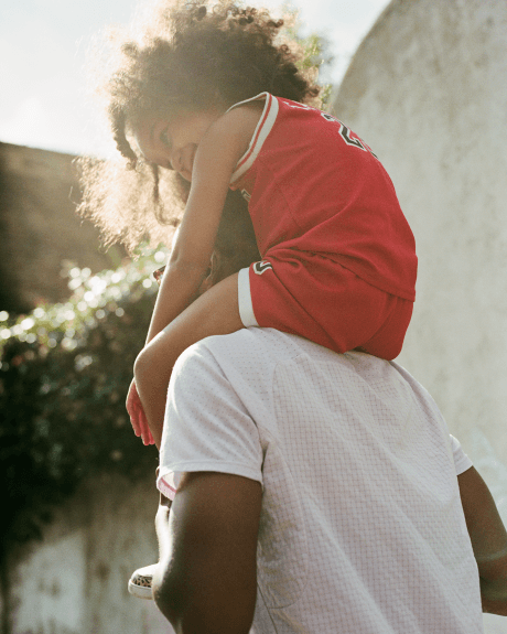 Parent carrying child on shoulders outdoors, representing the connection between TENCEL™ and collaborators and innovators